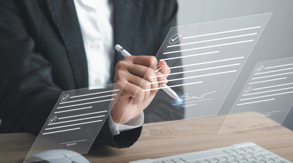 Digitale Signatur, Mann im Anzug der mit einem Stift ein digitales Dokument unterschreibt